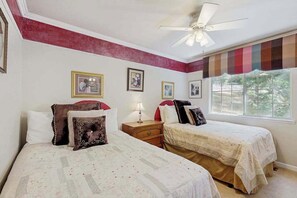 Ein Schlafzimmer mit zwei Betten, einem Deckenventilator und einem Fenster mit Blick.