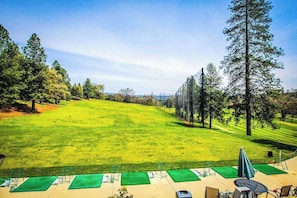 Ein Golfplatz mit freiem Blick auf die Spielbahn, Bäume und ein entferntes Gebäude.