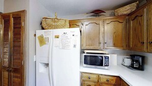 A kitchen with wooden cabinets, a white refrigerator, a microwave, and a coffee maker. - Top Deck Retreat - Huntington Lake (Lakeshore)