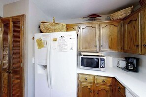 A kitchen with wooden cabinets, a white refrigerator, a microwave, and a coffee maker. - Top Deck Retreat - Huntington Lake (Lakeshore)