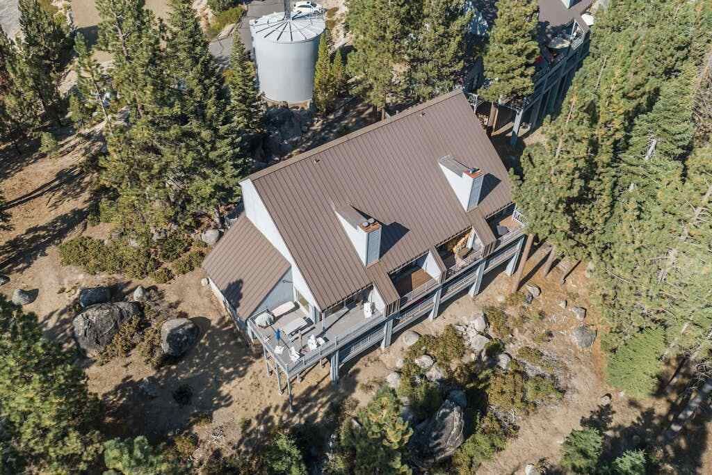 Un edificio de varios pisos con techo plano, rodeado de un bosque denso.