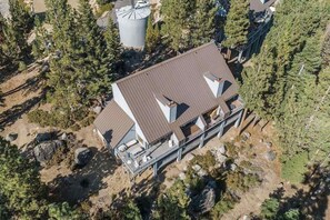 A multi-story building with a flat roof, surrounded by dense forest. - Top Deck Retreat - Huntington Lake (Lakeshore)