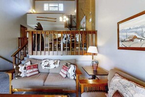 Un salon confortable avec un canapé, une table et un escalier menant à l’étage supérieur.