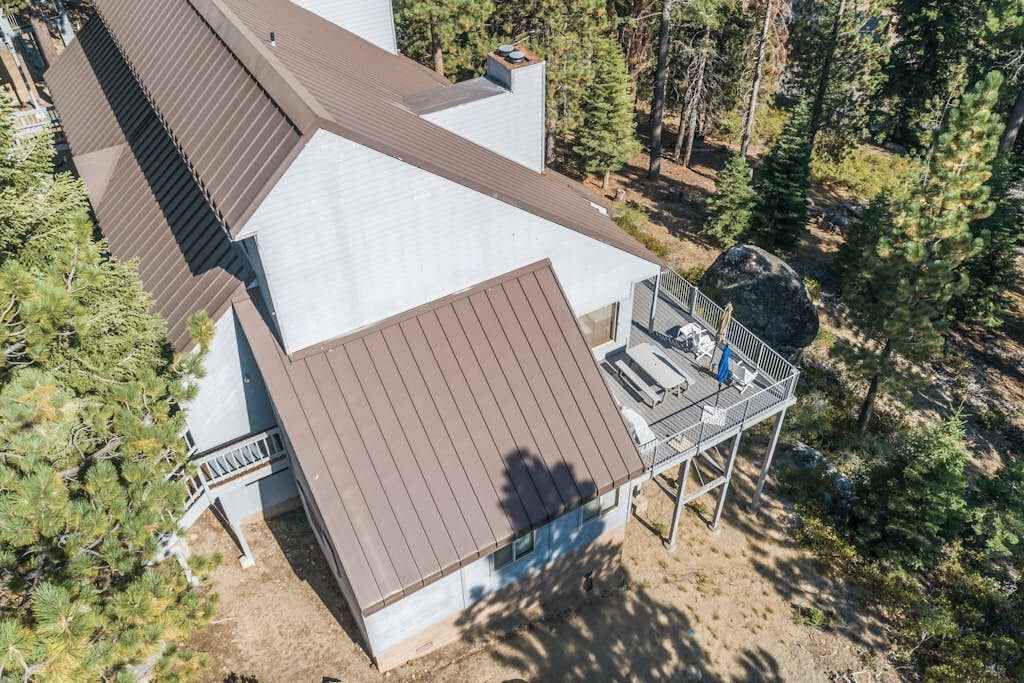 A two-story building with a brown roof, a balcony with a railing, and a clear view of the surrounding forest.