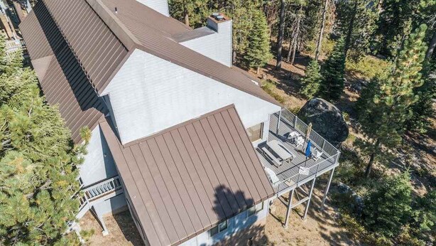 A two-story building with a brown roof, a balcony with a railing, and a clear view of the surrounding forest. - Top Deck Retreat - Huntington Lake (Lakeshore)