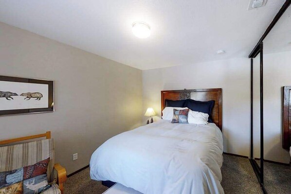 A hotel room with a bed, a nightstand, a lamp, a framed picture on the wall, and a window.