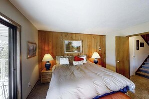 Une chambre à coucher avec un grand lit, deux lampes de chevet, un tableau au-dessus du lit et un lambris en bois.