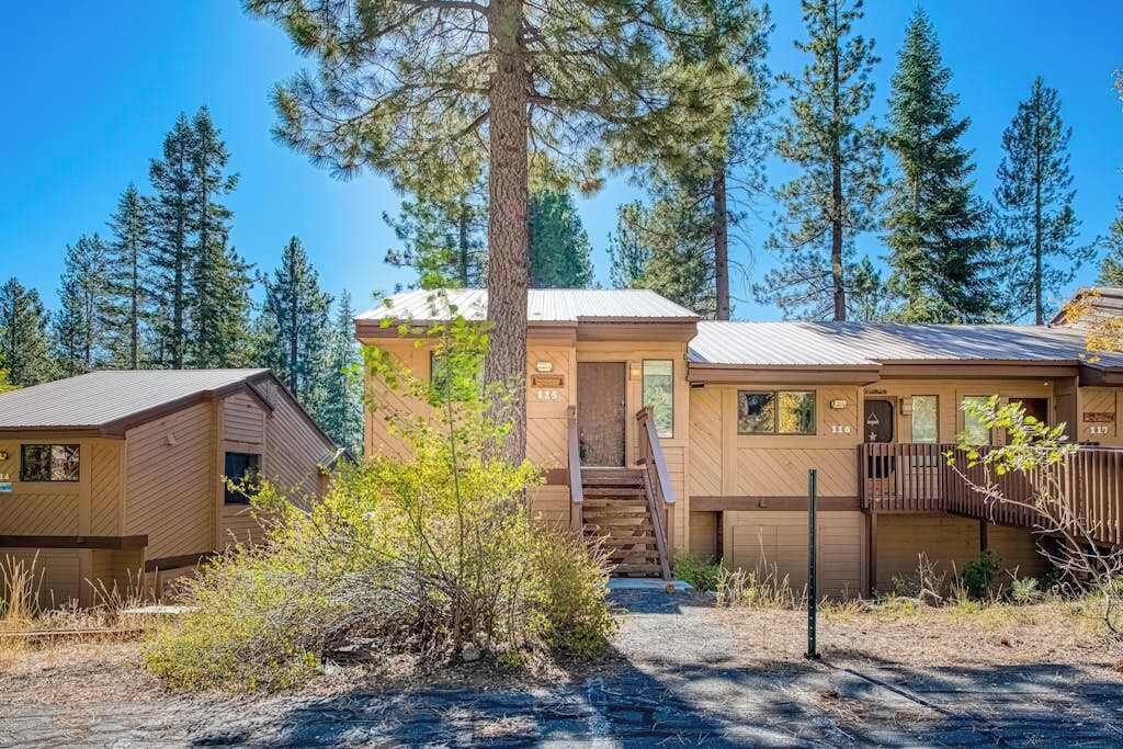 Une cabane avec une façade en bois, un porche à l’avant et un escalier menant à l’entrée.