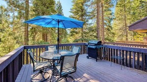 Eine Terrasse mit Tisch, Stühlen, einem Grill und einem Sonnenschirm.