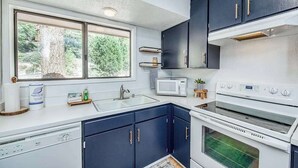 Eine moderne Küche mit dunklen Schränken, einer weißen Arbeitsplatte, einer eingebauten Mikrowelle und einem Doppelbackofen.