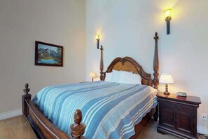 Une chambre à coucher avec un lit en bois, deux lampes de chevet, une table de chevet et un tableau accroché au mur.