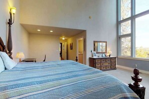 Een slaapkamer met een groot bed, een dressoir en een raam.