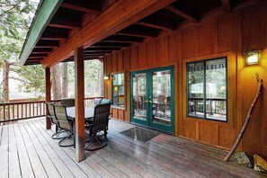 Eine Holzterrasse mit Tisch und Stühlen, ein überdachter Bereich mit Dach und eine Tür mit Fenster.