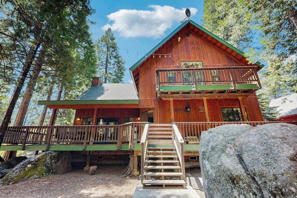 A wooden cabin with a balcony, surrounded by trees.