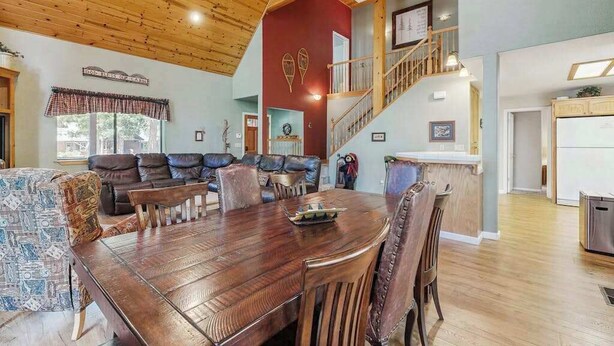 Un vaste espace de vie doté d’un plafond en bois, d’une table à manger et d’un escalier menant à un niveau supérieur.