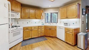 Une cuisine avec des meubles en bois, un four blanc, un four à micro-ondes et une fenêtre.