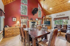 Een ruime woonkamer met een open haard, een opgehangen dierenhoofd en een televisie.