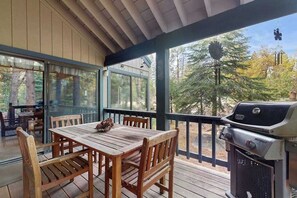 An outdoor deck with a wooden table and chairs, a grill, and a view of trees. - Whispering Pines - Sierra Cedars (Shaver Lake)