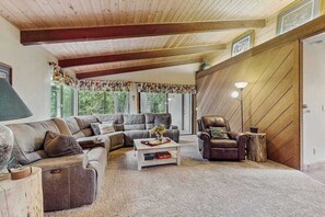 A spacious living room with a large sectional sofa, a coffee table, and a leather armchair. - Whispering Pines - Sierra Cedars (Shaver Lake)