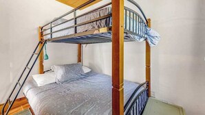 Ein Stockbett mit einer Leiter, einem Kopfkissen und einer Decke.