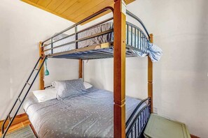 Ein Stockbett mit einer Leiter, einem Kopfkissen und einer Decke.