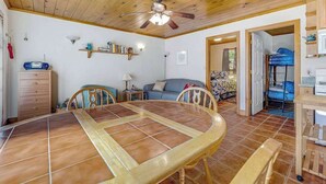 Ein Essbereich mit rundem Tisch und Stühlen, einem Deckenventilator sowie einer Küchenzeile mit Herd und Schränken.