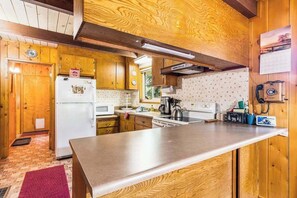 Eine Küche mit Holzausstattung, einem Kühlschrank, einer Mikrowelle und einem Herd.