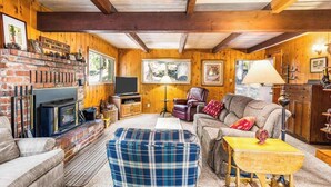 A cozy living room with a fireplace, comfortable seating, and wooden walls. - The Jug Handle Hideaway - Snowshoe Springs (Arnold)