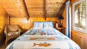 A wooden cabin room with a bed, a chair, and a window. - The Jug Handle Hideaway - Snowshoe Springs (Arnold)