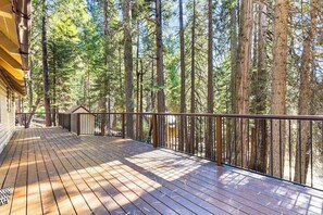 Eine Holzterrasse mit Metallgeländer, die auf einen Wald blickt.
