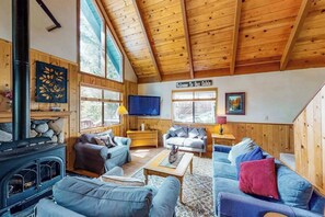Ein Ferienhäuschen, innen mit Holzbalkendecke, Kamin und zwei Sofas.