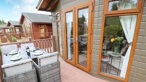 Eine überdachte Terrasse im Freien mit Korbmöbeln und einem Esstisch für vier Personen.