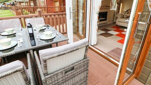 Eine Terrasse mit Essplatz, Korbstühlen und Blick auf Holzhütten im Hintergrund.