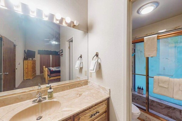 Un baño con un espejo grande, un lavamanos y una zona de ducha.