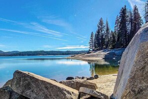 Eine natürliche Landschaft mit einem stillen See, felsigem Ufer und dichtem Wald.