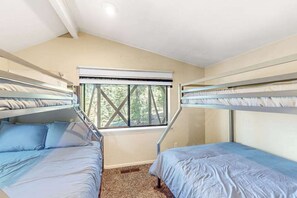 Ein Zimmer mit Etagenbetten, einem Fenster mit Blick auf Bäume und einer Deckenleuchte.