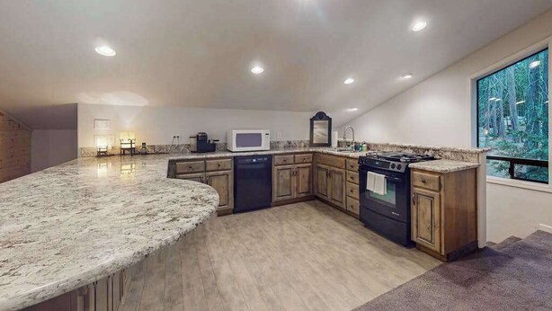 A kitchen with a granite countertop, wooden cabinets, a stove, and a microwave. - Tranquil Pines Estate - Ridgetop (Shaver Lake)