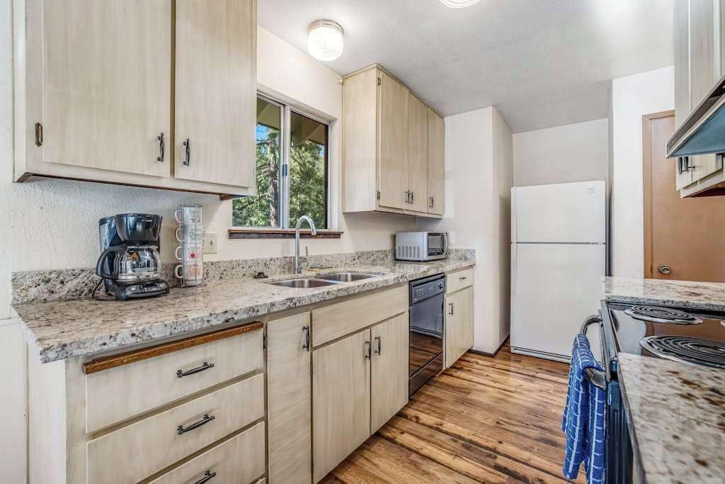 A compact kitchen with wooden cabinets, a microwave, a coffee maker, and a refrigerator.