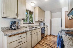 Eine kleine Küche mit Holzschränken, einer Mikrowelle, einer Kaffeemaschine und einem Kühlschrank.