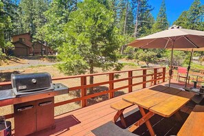 A wooden deck with a grill, picnic table, and umbrella. - Bryant Cabin - Blue Lake Springs (Arnold)