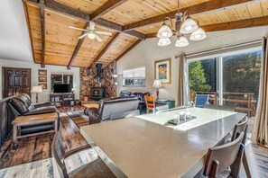 A spacious living area with a large dining table, leather sofas, and a fireplace. - Bryant Cabin - Blue Lake Springs (Arnold)