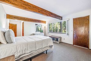 A bedroom with a bed, a bench, a window, and a door. - Bryant Cabin - Blue Lake Springs (Arnold)