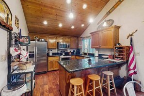 Eine Küche mit Holzausbau, einem Edelstahlkühlschrank, einer Mikrowelle und einer großen Kücheninsel mit Hockern.