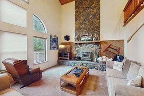 Una sala de estar con chimenea de piedra, sillón de cuero y una mesa de centro.