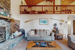 A cozy living room with a stone fireplace, a sofa, a coffee table, and a wooden ceiling. - Bearfoot Getaway - Sierra Cedars (Shaver Lake)