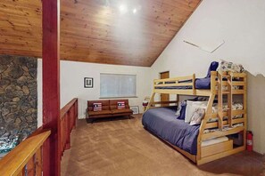 A room with a bunk bed, a sofa, a stone wall, and a wooden ceiling. - Bearfoot Getaway - Sierra Cedars (Shaver Lake)