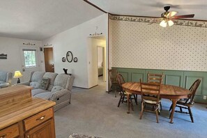 A dining area with a wooden table and chairs, a ceiling fan, and a patterned wall.