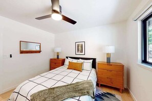 A bedroom with a bed, bedside tables, a ceiling fan, a window, and a wall-mounted mirror. - Piney Point - Meadowmont (Arnold)