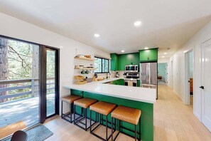A modern kitchen with a central island, bar stools, and a view of the outdoors. - Piney Point - Meadowmont (Arnold)