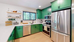 A modern kitchen with green cabinets, stainless steel appliances, and wooden countertops. - Piney Point - Meadowmont (Arnold)